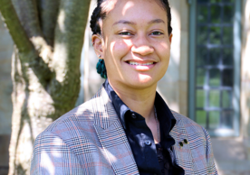 headshot of an bi-racial person with a tree and a window in the background 