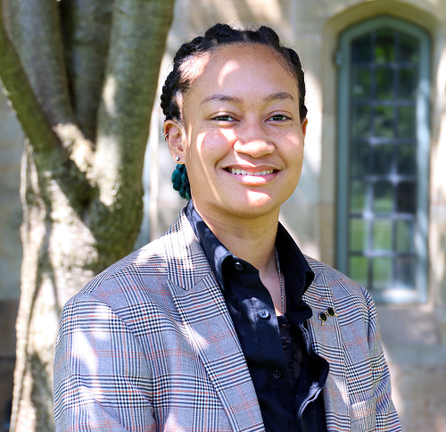 headshot of an bi-racial person with a tree and a window in the background 